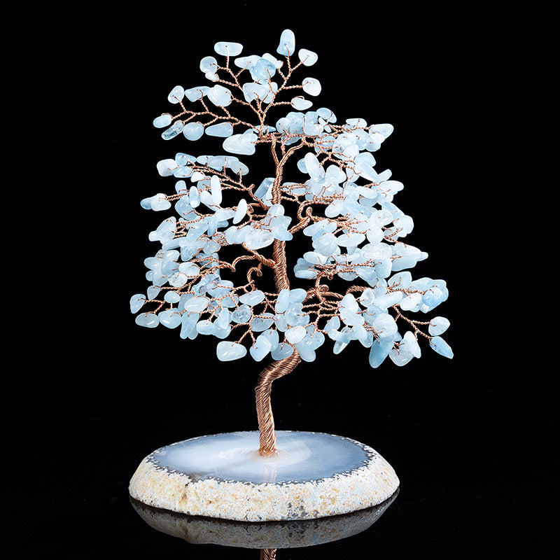 Decorative tree sculpture with blue stone leaves on a black background