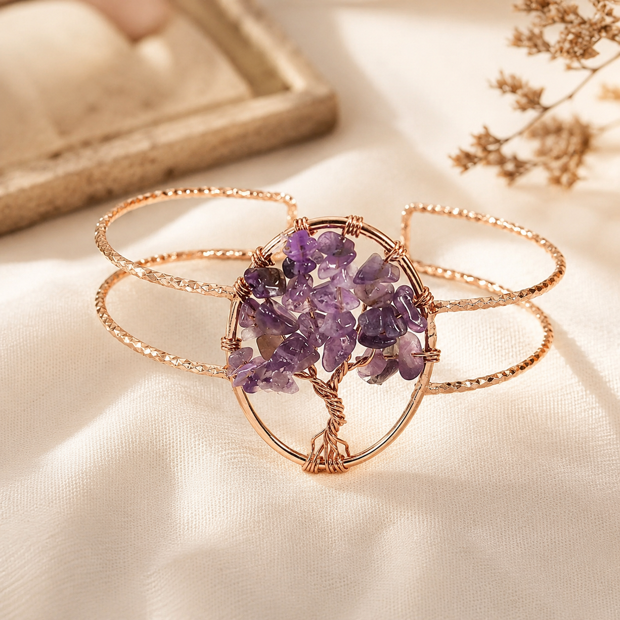 Rose gold wire-wrapped multi-band cuff bracelet featuring a central cluster of purple amethyst crystals, styled on a draped cream fabric background.