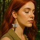 Woman with red hair wearing butterfly earrings in a forest setting