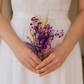 Person holding a small bouquet of flowers in a white dress.
