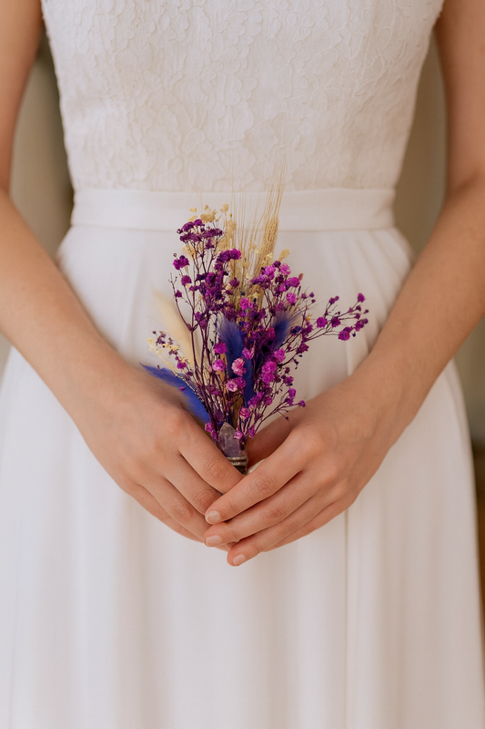 Person holding a small bouquet of flowers in a white dress.