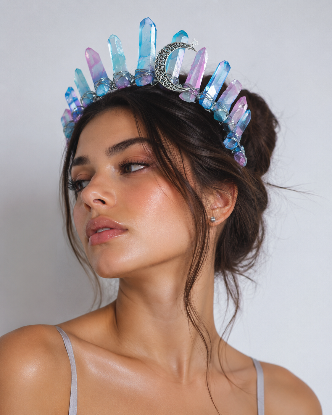 Woman wearing a colorful crystal crown against a plain background