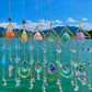 Decorative hanging crystal mobile with colorful stones against a blue sky and water background