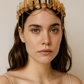 Woman wearing a gold headpiece with crystals against a neutral background