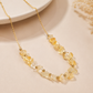 A gold chain necklace featuring a strand of clear, faceted crystal beads and small gold spacer beads, displayed on a warm beige surface.