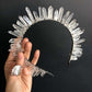Crystal headband held by a hand against a black background