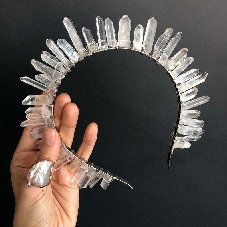 Crystal headband held by a hand against a black background