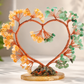 Decorative heart-shaped sculpture with orange and green elements on a neutral background