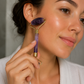 Woman using a purple facial roller on her face
