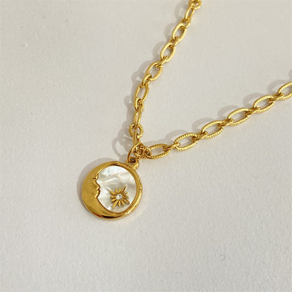 Gold necklace with a moon and sun pendant on a light gray background