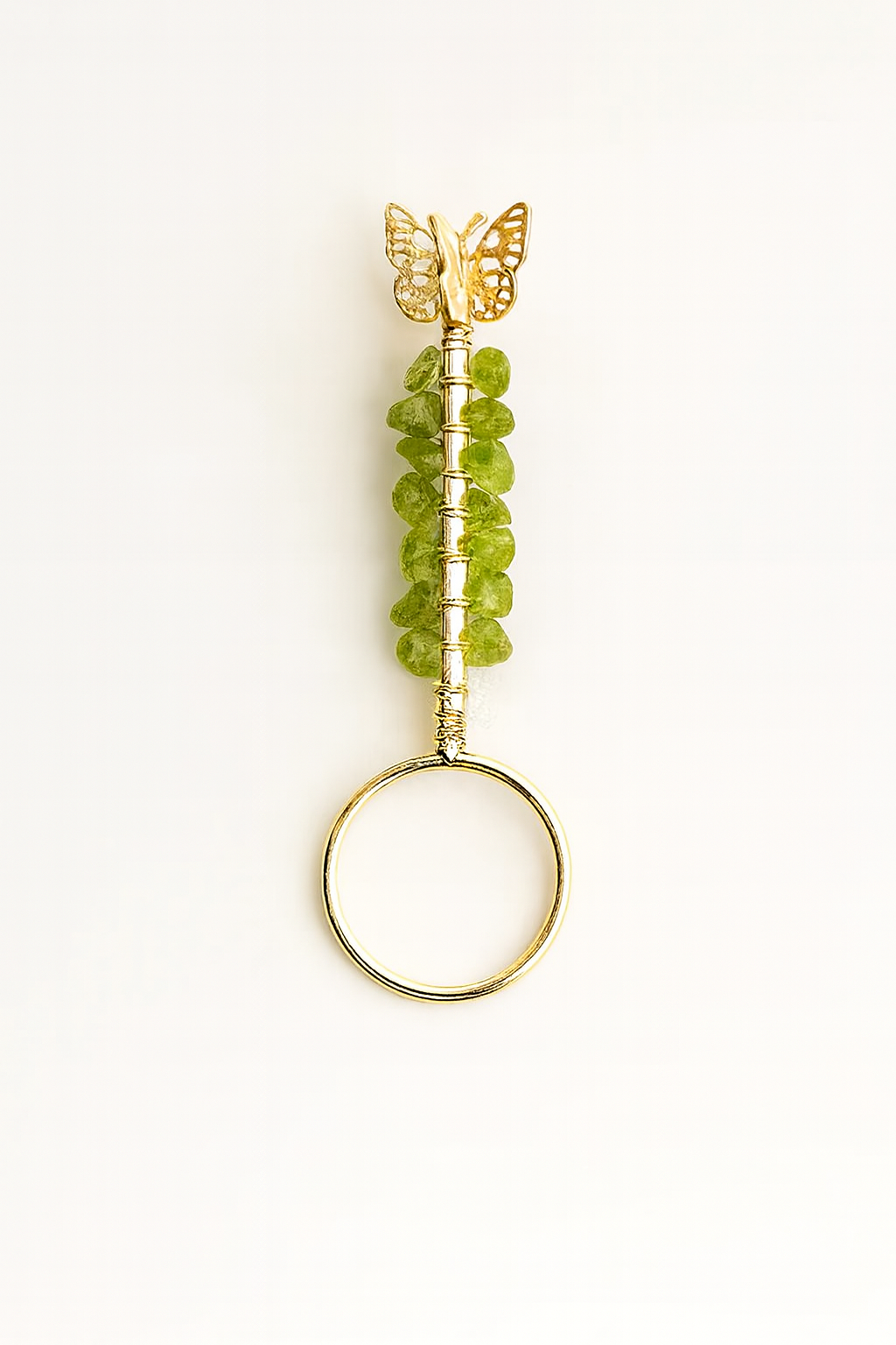 Decorative ring with green beads and a gold butterfly on a white background