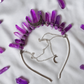 A headband necklace featuring multiple purple amethyst crystal points and a silver crescent moon charm, laid flat on a white fabric background with scattered loose crystals.