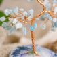 Decorative tree sculpture with blue and white stones on a natural stone base
